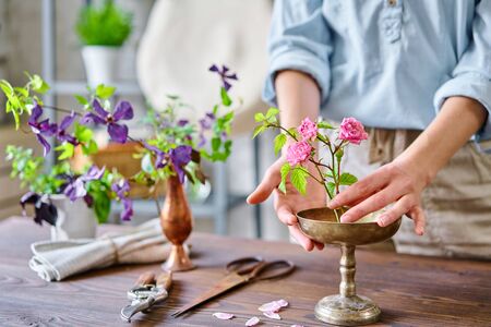 Ikebana in kenzan, scissors and pruner on the table florist. Seasonal summer garden flowers. A young woman florist create flower arrangementの写真素材