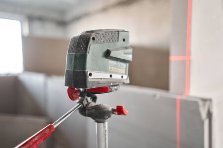 The construction worker Measures horizon level with a laser level. Construction of internal walls in the apartment using a plaster concrete plate with groove ridge. Gypsum plateの写真素材