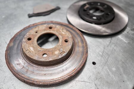 Old used and new to change for safety car brake disc and pad on metal table of an auto mechanic. Auto repair concept.の写真素材