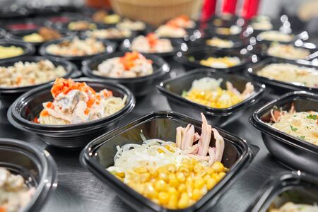 Row of plastic disposable lunch box with healthy natural food. Soups, cream soup, main course with...