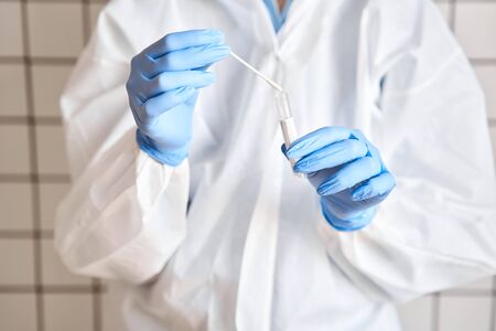 Doctor holding swab test tube for 2019-nCoV analyzing. Coronavirus test. Blue medical gloves and...