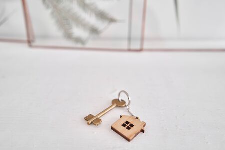 House key and keychain in the form of homes lies on wooden boards. Concept for real estate,...