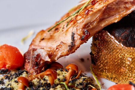 Pork meat on the bone with baked potatoes decorated with pickled cherry tomatoes. Photos for cafe and restaurant menusの写真素材