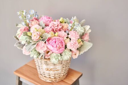 Beautiful flower composition a bouquet in a wicker basket. Floristry concept. Spring colorsの写真素材