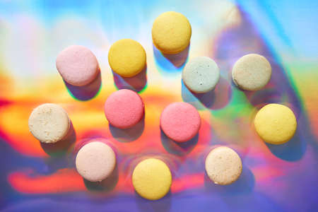 French cake macaron. Set of cute sweets on colorful rainbow background. almond cookies, pastel colors, top viewの写真素材