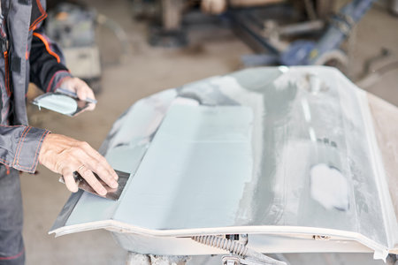 Repairing car body, Application putty close up. The mechanic repair the car. Work after the accident by working sanding primer before painting.の写真素材