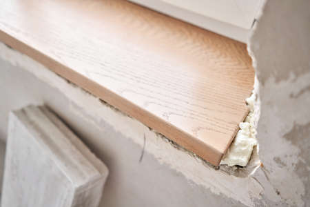Wooden window sill, plywood covered with oak veneer. Window sill installation process. Interior design, building, home improvement, diy concept.の写真素材