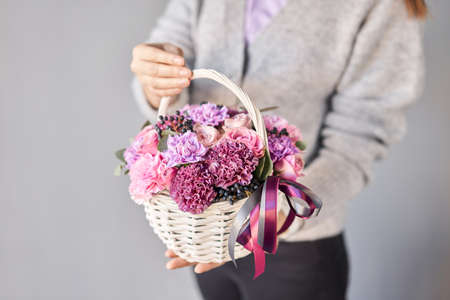 Flower arrangement in Wicker basket. Beautiful bouquet of mixed flowers in woman hand. Handsome fresh bouquet. Small flower shop and Flowers delivery.の写真素材