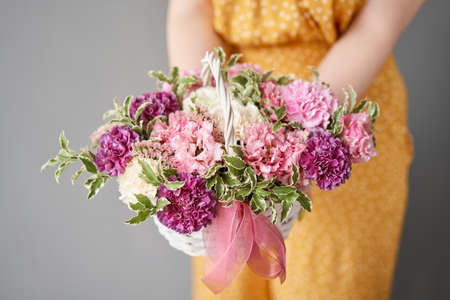 Flower arrangement in Wicker basket. Beautiful bouquet of mixed flowers in woman hand. Handsome fresh bouquet. Small flower shop and Flowers delivery.の写真素材