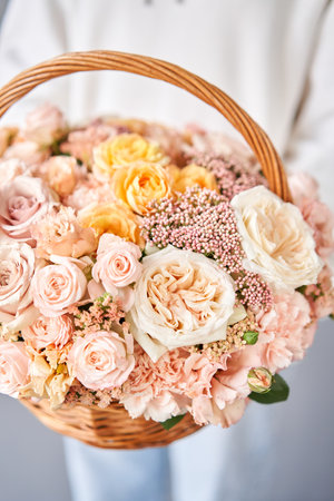 Flower arrangement in Wicker basket. Beautiful bouquet of mixed flowers in woman hand. Handsome fresh bouquet. Small flower shop and Flowers delivery.の写真素材