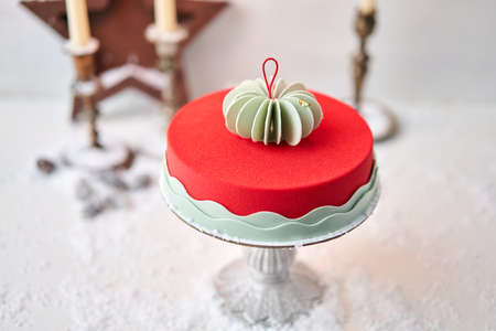 Mousse cake covered with red velour. Dessert on a snow-covered table. Modern european cake. French cuisine. Christmas theme. Copy spaceの写真素材
