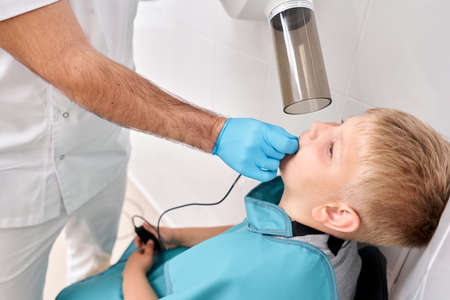 Radiographer taking teeth radiography to a boy using digital x-ray machine in pediatric dental...