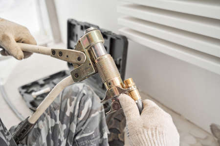 Plumber clamps the connectors on the pipe. connection heating pipes to white Radiator in a new...