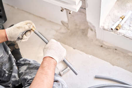 Plumber clamps the connectors on the pipe. connection heating pipes to white Radiator in a new...