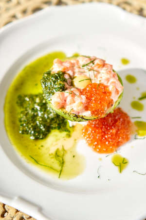 Raw salmon tartare. Fresh salmon, avocado and pesto sauce with red caviar on a plate. Selective focusの写真素材