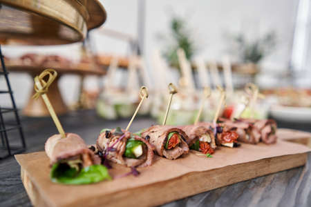 Delicious canapes with pork ham with dried tomatoes. Tasty buffet table. Summer party. Catering...