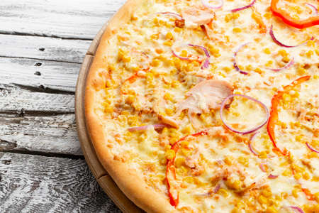 Pizza with chicken, paprika and corn. Italian kitchen and cooking concept. Chief with a pizza cutter cutting pizza to pieces at Neapolitan pizzeria.の写真素材