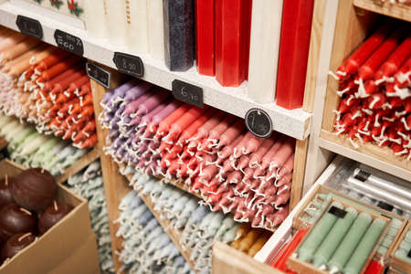 Many multicolored colorful paraffin stick Pastel colors candles arranged in shelves lying on shelter and sorted by color in a household candle shop store market.の写真素材