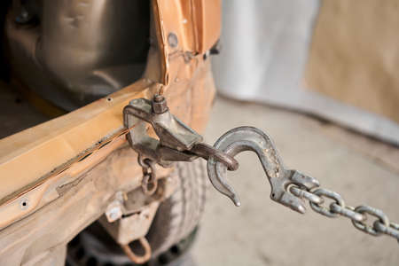 A broken car with a violation of geometry is on the stocks for leveling. Restoration of vehicles with chain and hook. Repair in the workshop and autoの写真素材