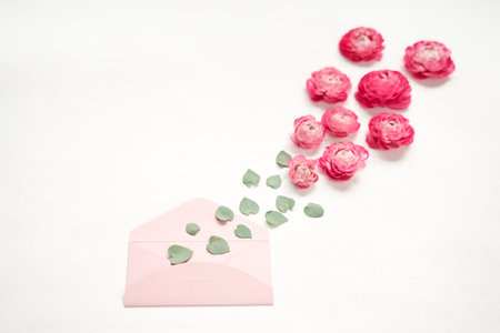 Love letter. Pink paper envelope mock up. Petals of flowers, roses and ranunculus. Valentines day romantic background . Space for text.の写真素材