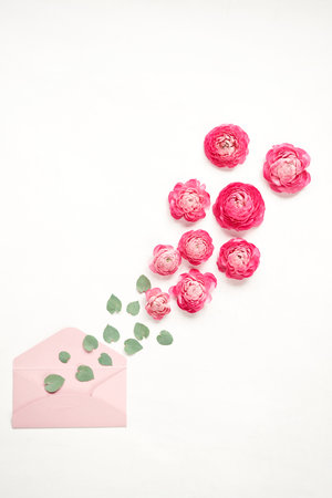 Love letter. white card with pink paper envelope mock up. Petals of flowers, roses and ranunculus....