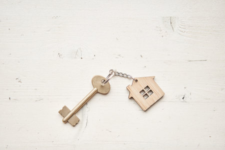 Key with house shaped keychain. Modern light lobby interior. Mortgage concept. Real estate, moving...