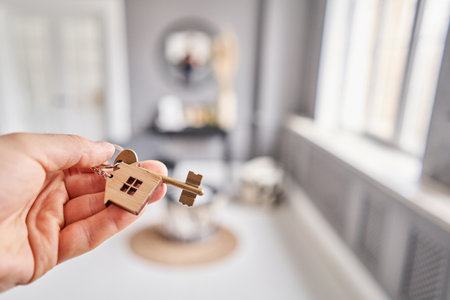 Concept of renting an apartment. House key in man hand. Young man. Modern light lobby interior. Real estate, hypothec, moving home or renting property.の写真素材