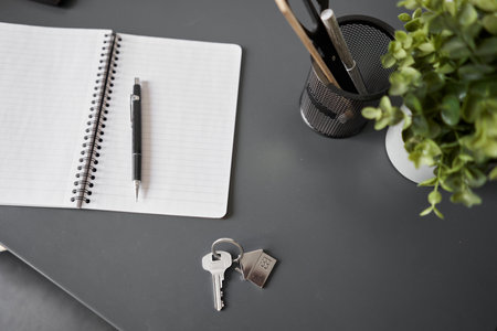 Key with house shaped keychain on table . Modern light apartment interior. Mortgage concept. Real...