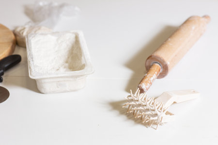 A kitchen tool for making dough. Dough for pizza, the chef rolls out the blanks. Closeup hand of chef baker in uniform white apron cook pizza at kitchenの写真素材