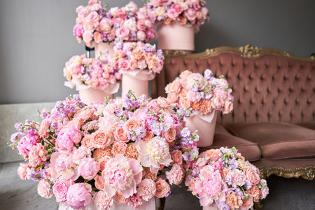 A gift set of boxes with flowers in a beautiful interior on the background of a sofa. Flowers as a gift to your beloved woman. The flower room. A box of flowers for Mothers Day.の写真素材