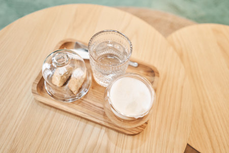 Coffee with milk, a cookie and a glass with water on a wooden table. Cup of coffee cappuccino with cantuccini and a glass of water on a wooden tray.の写真素材