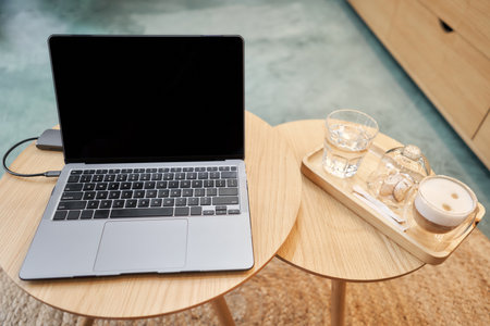 A cup of coffee next to laptop. A cup of hot cappuccino coffee with cookies and a laptop computer on...