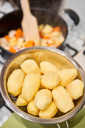 Peeled potatoes ready for cooking. Chicken breast in pieces with potatoes and carrot in a saucepan simmer on low heat. Home cooking. Healthy food, cooked without oil and salt.の写真素材
