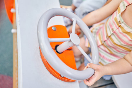 Little girl playing, she is a car driver holding steering wheel on playground. A sunny summer evening, a fun childhood.の写真素材