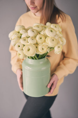A bouquet of pale pink ranunculus flowers variety Hanoi. Persian buttercup in a vase in woman hand. The work of a florist in a flower shop.の写真素材