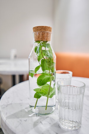 A refreshing drink on a hot summer day. A table in a cafe. A decanter and two glasses. Healthy drinks, diet, detox with fruit water in glass bottle with mintの写真素材