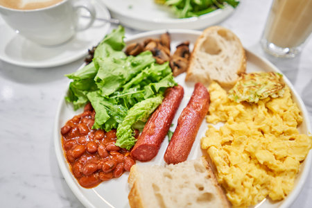 Simple American style Breakfast with sausages, scrambled eggs, baked beans, mushrooms and tomatoes....