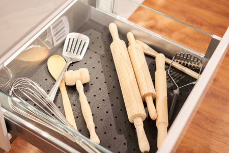 Kitchen utensil cutlery drawer organizer tray with simple set of tools, minimalist order. Open drawer with different utensils and folded towels. Order in kitchen. Kitchen furniture store.の写真素材