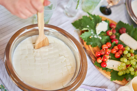 Master class and cheese tasting. Women make cheese. The enzyme and starter culture are added to the milk in a metal container. Milk folding process, home production, business, entrepreneur.の写真素材