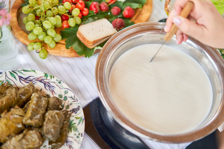 Cut with a knife, separate the serum. Master class and cheese tasting. Women make cheese. The enzyme and starter culture are added to the milk in a metal container. Milk folding process, home production, business, entrepreneur.の写真素材