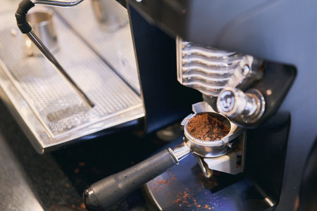 The coffee grinder crushed the grains for a portion of espresso. A small coffee business. Makes espresso, Americano with a takeaway. A professional barista prepares coffee in a carob coffee machine. Favorite job in the restaurant industry.の写真素材