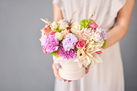 Flower arrangement in round box. Beautiful bouquet of mixed flowers in woman hand. Floral shop concept . Handsome fresh bouquet. Flowers deliveryの写真素材