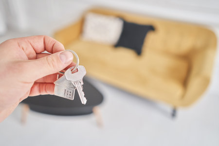 Concept of renting an apartment. House key in man hand. Young man. Modern light lobby interior. Real...