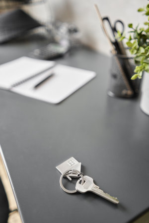 Key with house shaped keychain on table . Modern light apartment interior. Mortgage concept. Real...