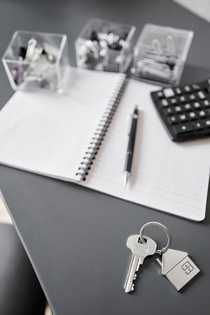 Key with house shaped keychain on table . Modern light apartment interior. Mortgage concept. Real...
