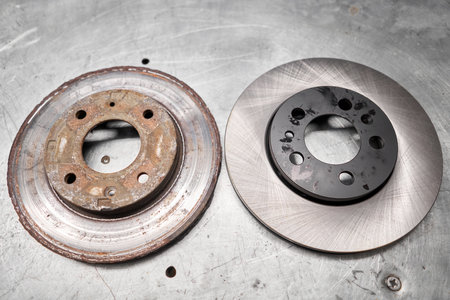 Old rusty brake disc and new disc. Change the old to new brake disc on car in a garage. Auto repair concept.の写真素材