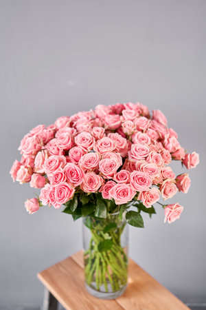 Glass vase with bush spray roses. The florist takes care of the flowers. A girl with a vase of flowers in her hands.の写真素材