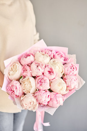 A bouquet of white and pink peonies in womens hands. Flower delivery. A beautiful bouquet of flowers as a gift for a holiday.の写真素材