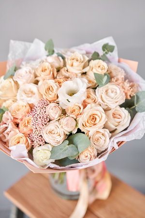 Beautiful bouquet of fresh flowers in glass vase on wooden table. A gift bouquet in mix color scheme for any holiday. The concept of a small flower shop. Flower and gift deliveryの写真素材