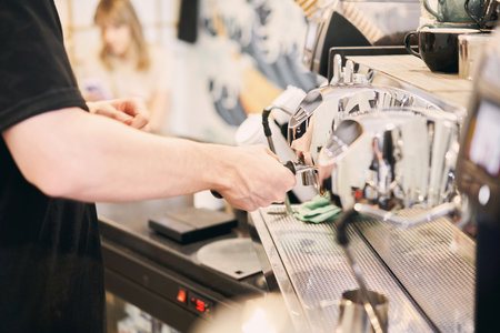 A small coffee business. Makes espresso, Americano with a takeaway. A professional barista prepares coffee in a carob coffee machine. Favorite job in the restaurant industry.の写真素材
